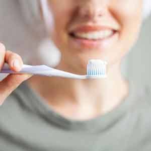 a woman holding a toothbrush with toothpaste