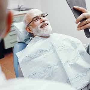 a patient checking his new teeth with a mirror