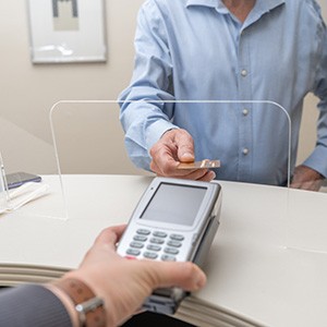 A man paying the cost of root canal treatment with a credit card