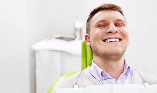 Male dental patient sitting in green chair
