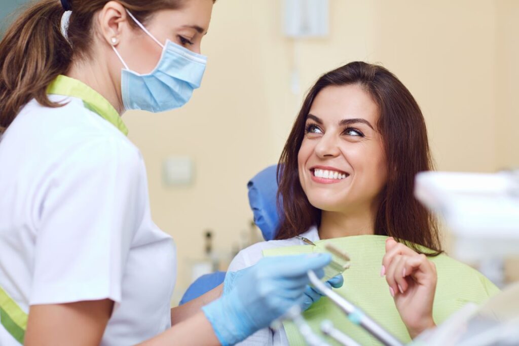 A woman in a dental chair talking to a female dentist.